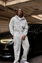 Heather Grey PTW Essential Zip Hoodie with a white chest logo, worn with grey sweatpants